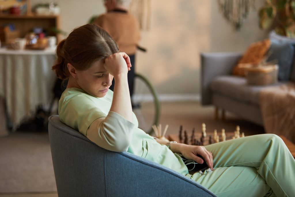 exhausted young woman sitting in a chair with a hand on her head